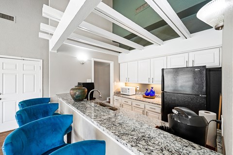 a kitchen with a long counter and blue chairs